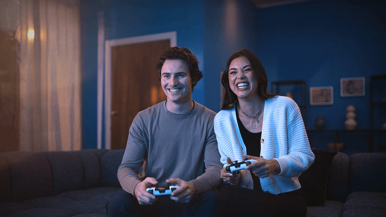 Два человека играют дома с контроллерами DualSense