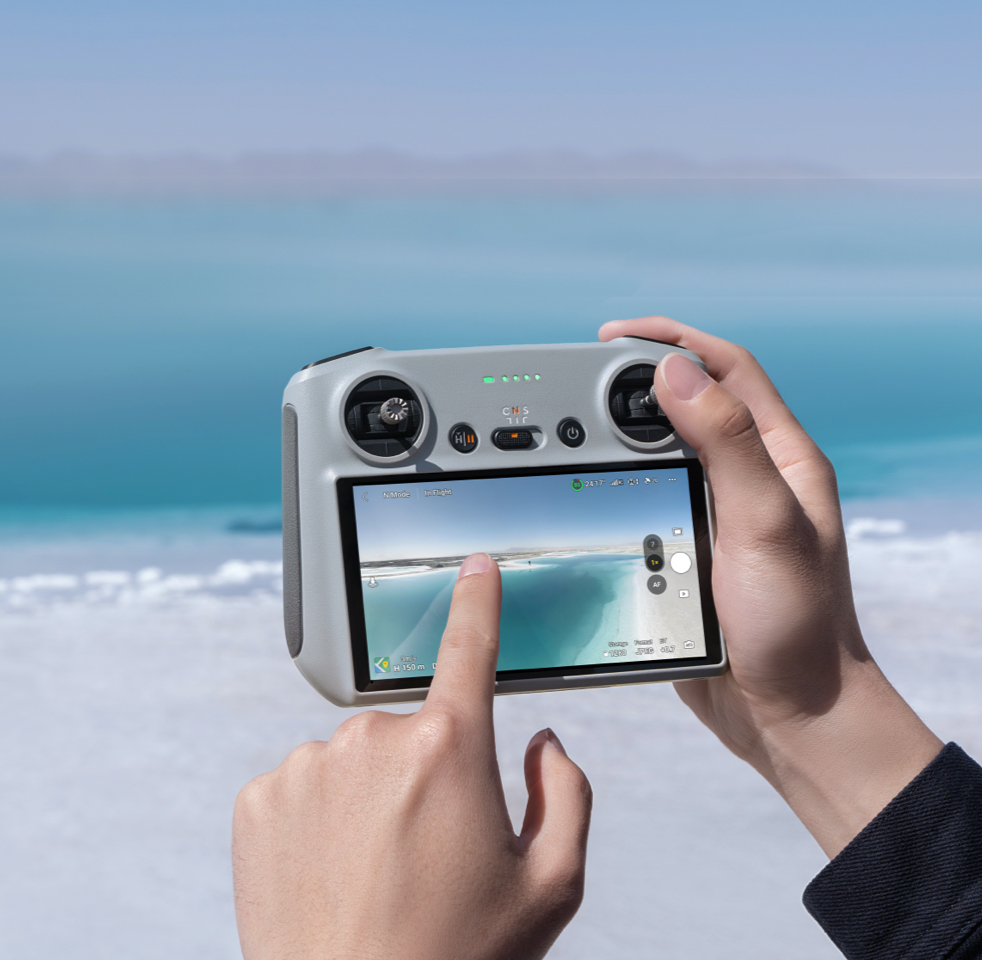 DJI RC в руках при управлении съёмкой на побережье